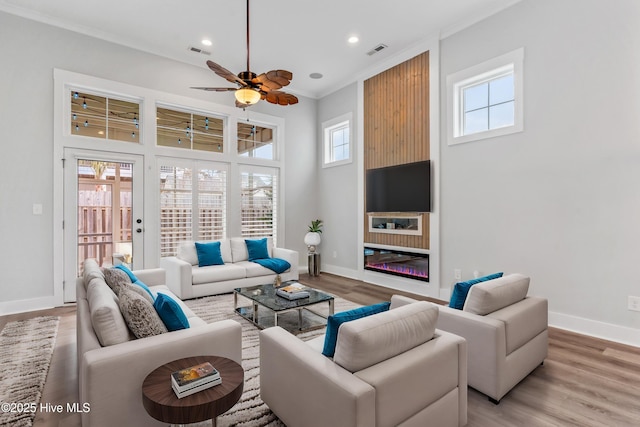 living area featuring visible vents, a fireplace, light wood-type flooring, and crown molding