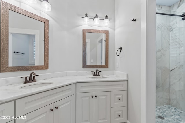 full bathroom with a marble finish shower, double vanity, and a sink