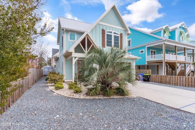 view of front of property with fence, board and batten siding, an outdoor structure, concrete driveway, and metal roof