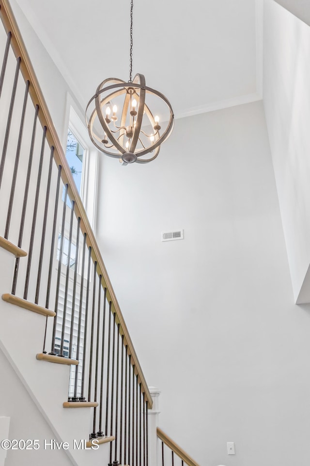 stairs featuring visible vents, an inviting chandelier, a towering ceiling, and crown molding