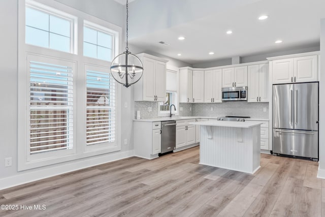 kitchen featuring a sink, light wood-style floors, appliances with stainless steel finishes, white cabinets, and light countertops