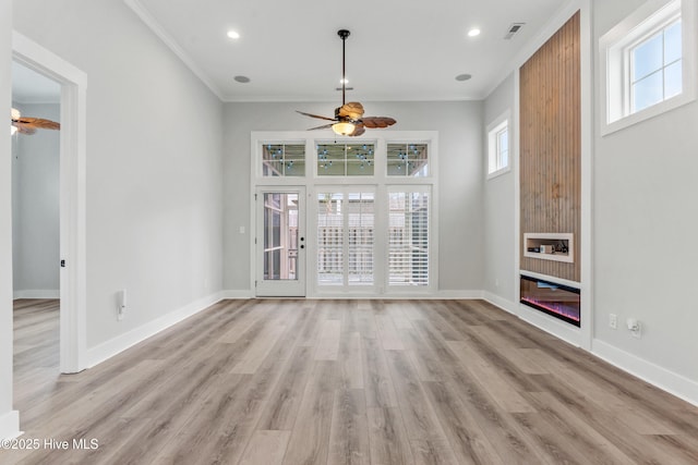 unfurnished living room featuring light wood finished floors, a glass covered fireplace, baseboards, and ceiling fan