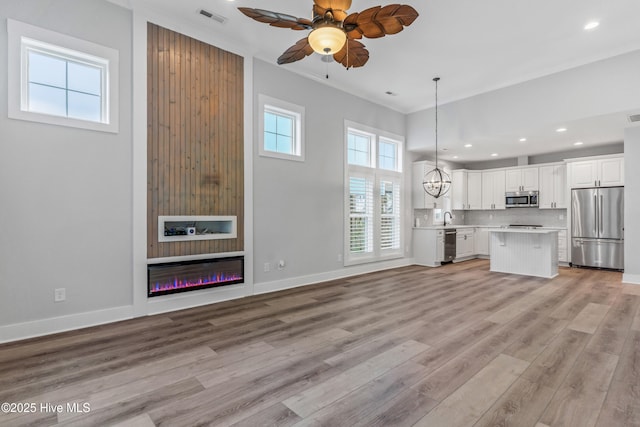 kitchen with visible vents, light wood-type flooring, light countertops, a glass covered fireplace, and stainless steel appliances