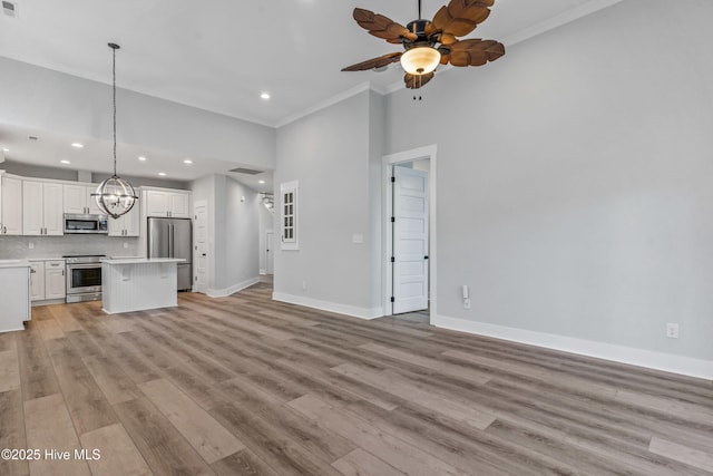 unfurnished living room featuring crown molding, baseboards, recessed lighting, ceiling fan with notable chandelier, and light wood-style floors