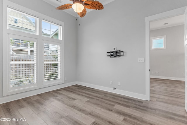 spare room with baseboards, wood finished floors, and a ceiling fan