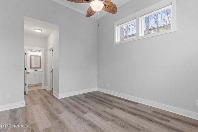 unfurnished bedroom featuring ensuite bath, crown molding, wood finished floors, and baseboards