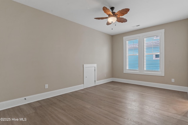 spare room with visible vents, wood finished floors, baseboards, and ceiling fan