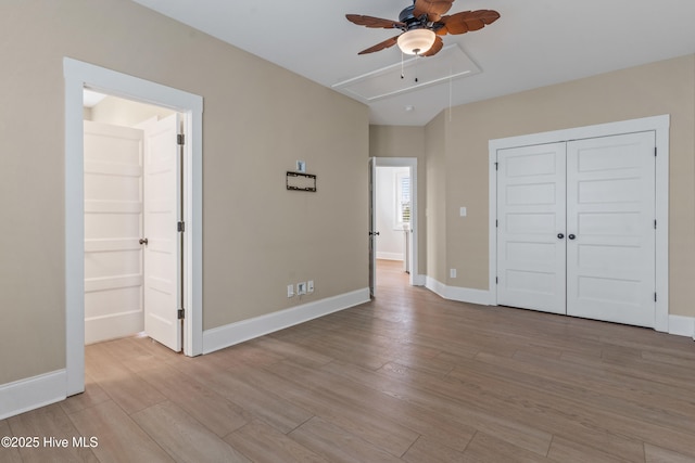 unfurnished bedroom with attic access, baseboards, and wood finished floors