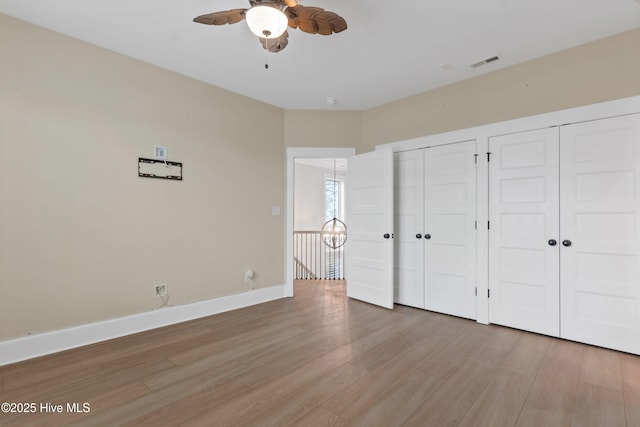 unfurnished bedroom with light wood finished floors, visible vents, two closets, ceiling fan, and baseboards