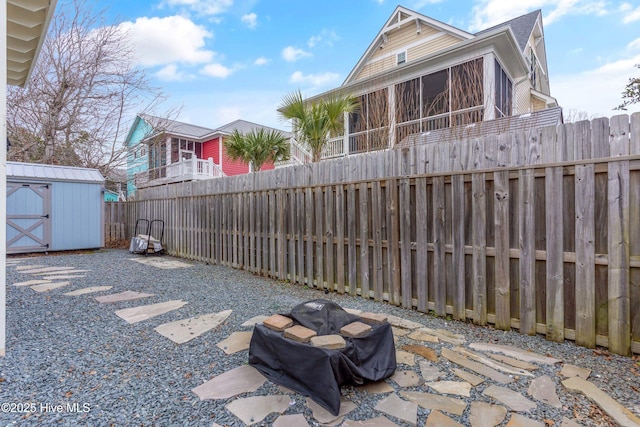 view of patio with an outbuilding, a storage shed, a fenced backyard, and a sunroom