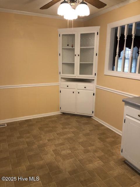 unfurnished dining area with crown molding and ceiling fan