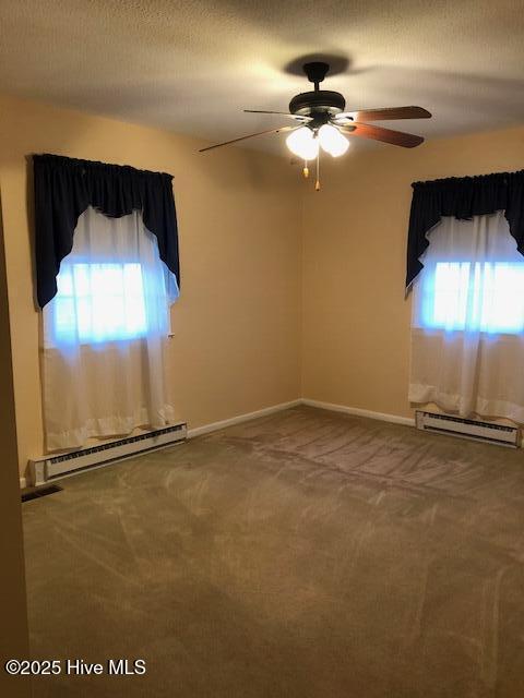 carpeted empty room featuring ceiling fan, a textured ceiling, and baseboard heating