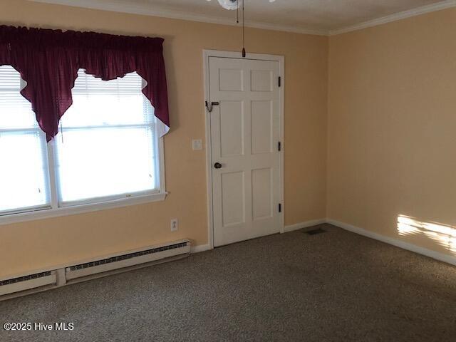 carpeted spare room with baseboard heating and crown molding