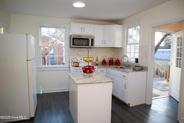 kitchen featuring sink, white appliances, white cabinetry, backsplash, and a kitchen island
