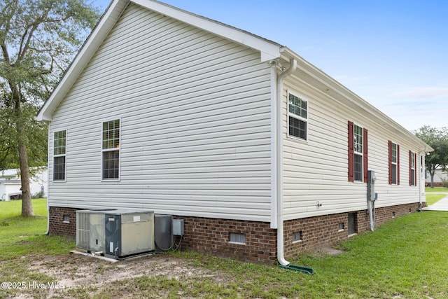 view of side of home with central AC unit and a yard