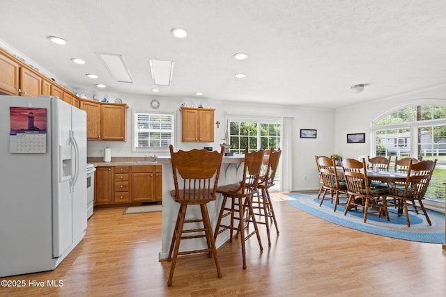 kitchen featuring sink, white appliances, plenty of natural light, and light wood-type flooring