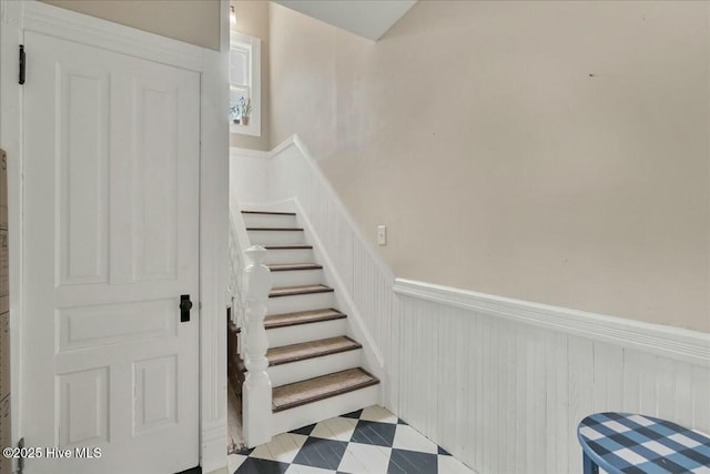 staircase with wainscoting and tile patterned floors