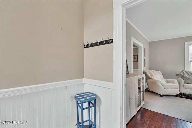 interior space with a wainscoted wall, dark wood finished floors, and crown molding