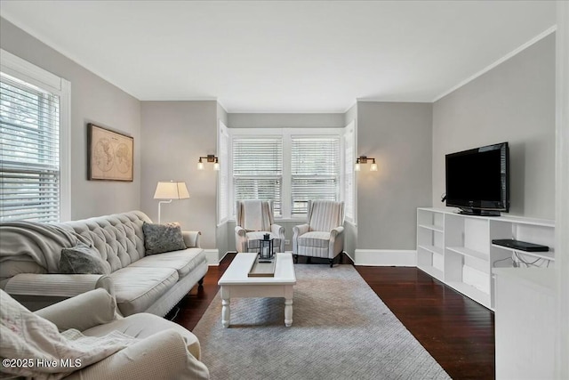 living area with baseboards, ornamental molding, dark wood-style flooring, and a healthy amount of sunlight