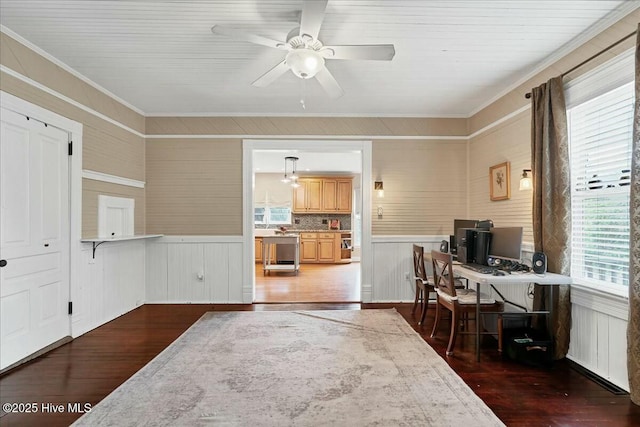 office with a ceiling fan, dark wood-style flooring, wainscoting, and crown molding