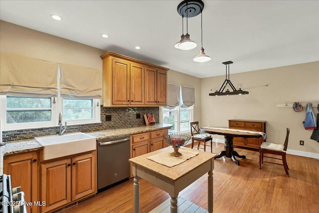 kitchen featuring decorative backsplash, dishwasher, light wood finished floors, and a sink