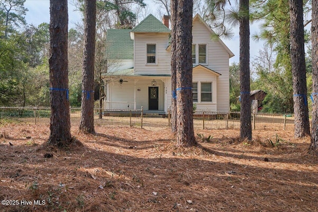 view of front facade with a fenced front yard, a porch, and a chimney