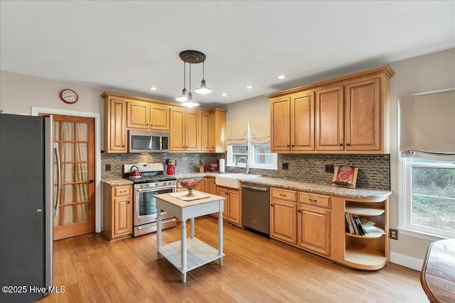 kitchen featuring light wood-type flooring, tasteful backsplash, stainless steel appliances, and a sink