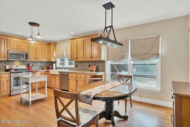 kitchen featuring a healthy amount of sunlight, light wood-style floors, appliances with stainless steel finishes, and backsplash