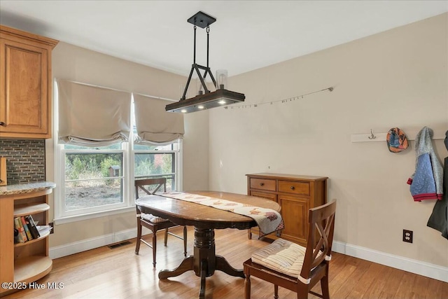 dining area with baseboards, visible vents, and light wood-style floors