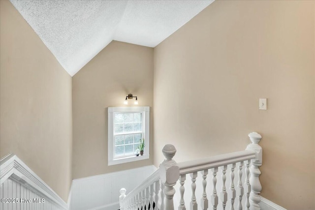 stairs featuring lofted ceiling and a textured ceiling