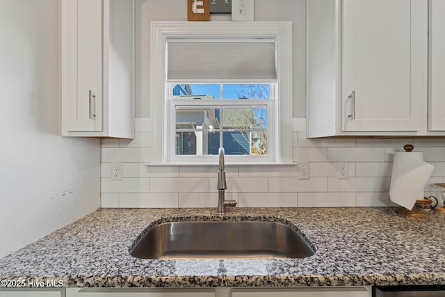 kitchen featuring white cabinetry, sink, tasteful backsplash, and dark stone counters