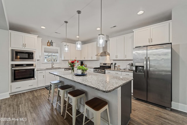 kitchen featuring white cabinets, appliances with stainless steel finishes, sink, and wall chimney range hood