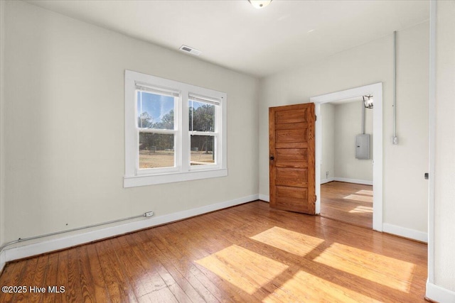 spare room featuring a baseboard radiator, electric panel, and light hardwood / wood-style floors