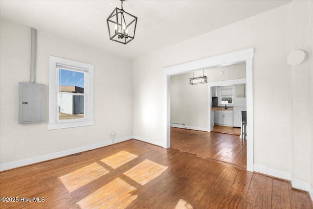 unfurnished dining area with hardwood / wood-style flooring, electric panel, and a notable chandelier