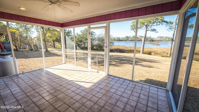 unfurnished sunroom featuring ceiling fan and a water view