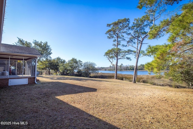 view of yard with a sunroom and a water view