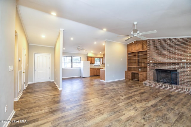 unfurnished living room featuring vaulted ceiling, wood-type flooring, ceiling fan, crown molding, and a brick fireplace