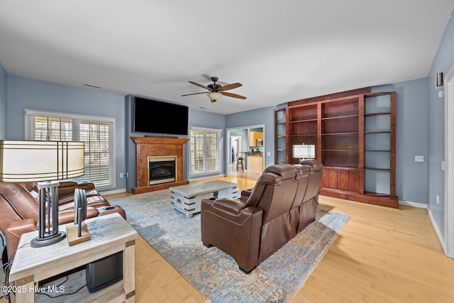 living room featuring a wealth of natural light, light wood-type flooring, and ceiling fan