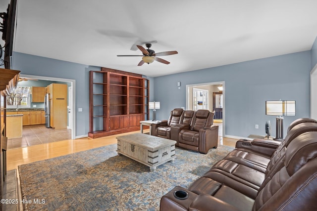 living area featuring light wood-style floors, baseboards, and ceiling fan