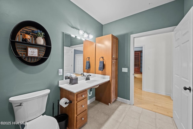 half bathroom with toilet, baseboards, and a sink