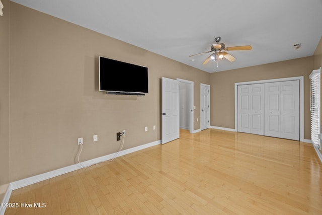 unfurnished bedroom with light wood finished floors, a closet, a ceiling fan, and baseboards