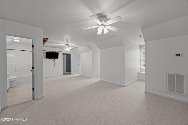 additional living space featuring visible vents, baseboards, light colored carpet, lofted ceiling, and a ceiling fan