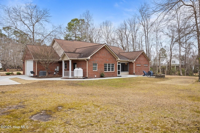 single story home with cooling unit, a fire pit, a front yard, a garage, and brick siding