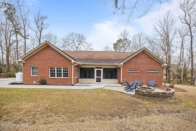 back of property featuring brick siding, a patio area, a lawn, and a fire pit