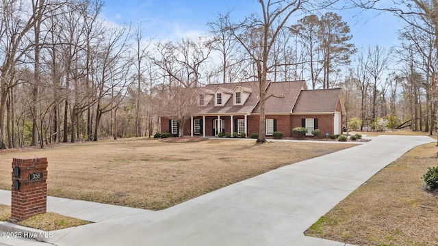 view of front of home with a front yard, a porch, brick siding, and driveway