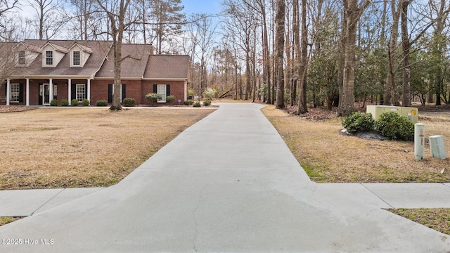 view of front of home featuring a front yard, brick siding, and driveway