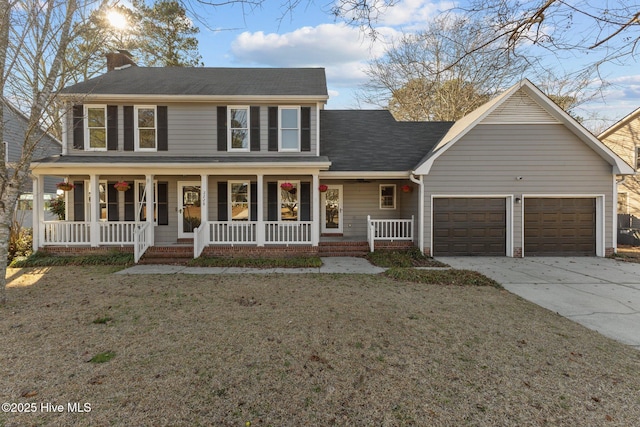 colonial house with covered porch, a garage, driveway, a front lawn, and a chimney