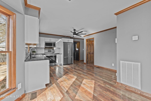 kitchen featuring visible vents, dark countertops, appliances with stainless steel finishes, white cabinetry, and a sink