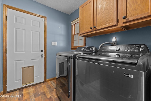 laundry room with dark wood-style flooring, washing machine and clothes dryer, cabinet space, a textured ceiling, and baseboards