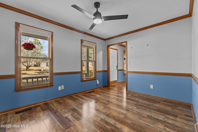 spare room with ceiling fan, wood finished floors, visible vents, baseboards, and crown molding